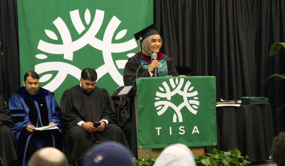 TISA graduate speaking at the commencement podium